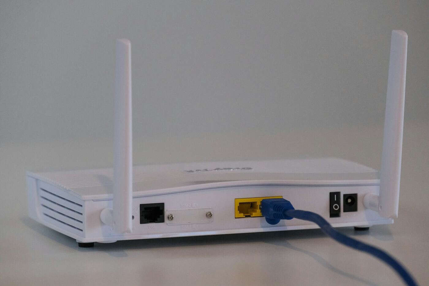 A broadband internet router with an Ethernet cable plugged into the back