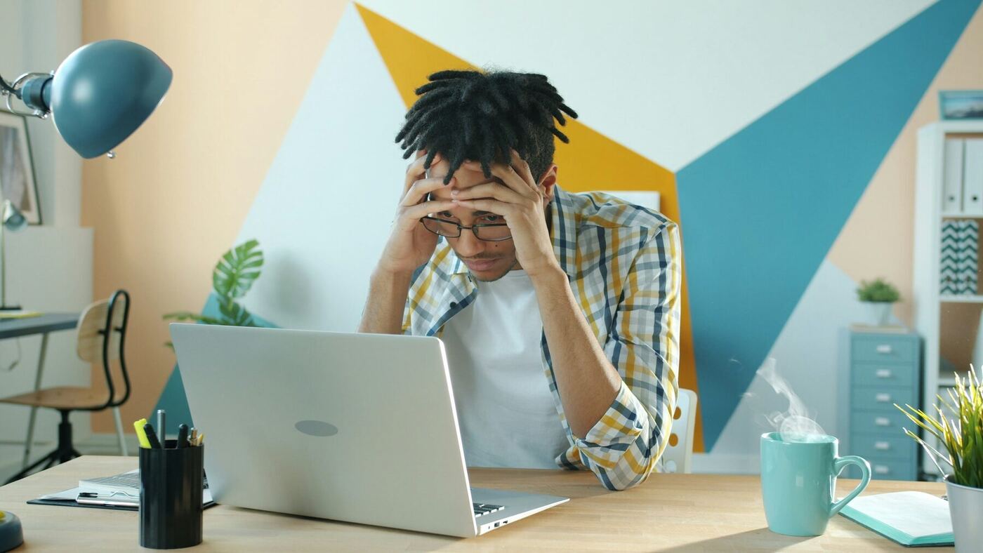 A frustrated person at a laptop with steam rising from a hot coffee cup