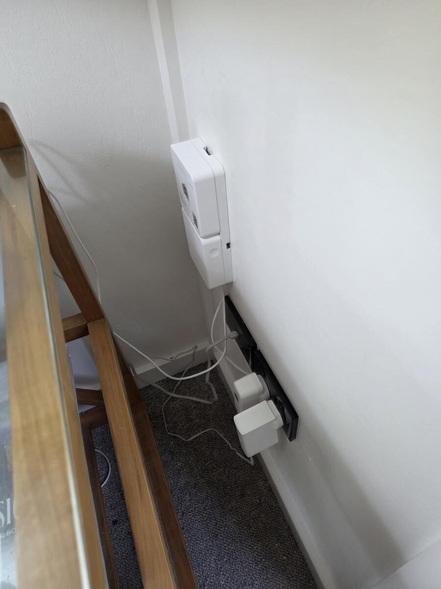An NBN connection box installed low on a wall behind furniture