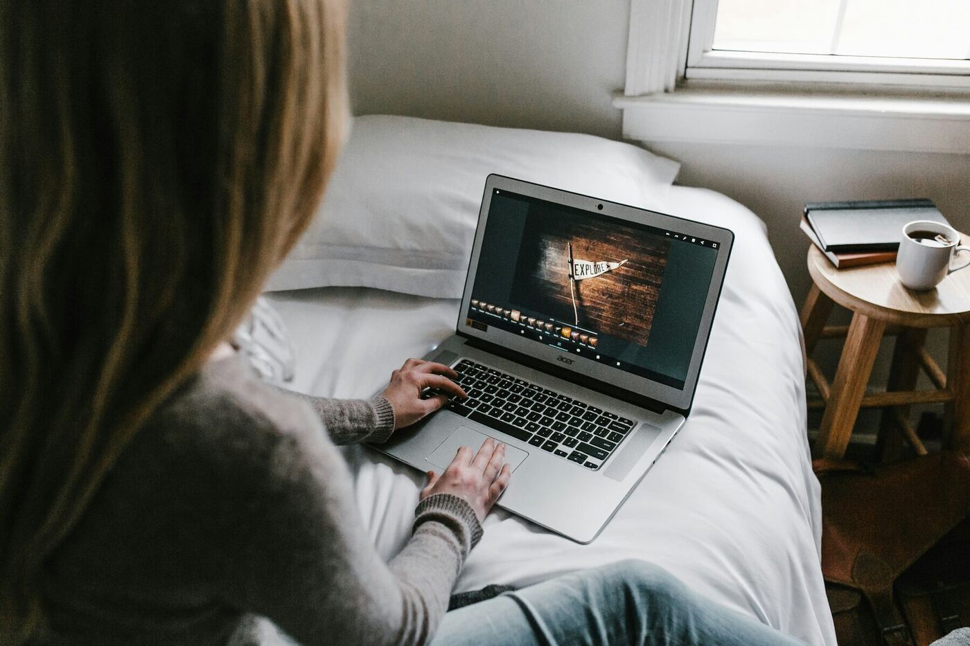 Young person using a laptop alone on a bed