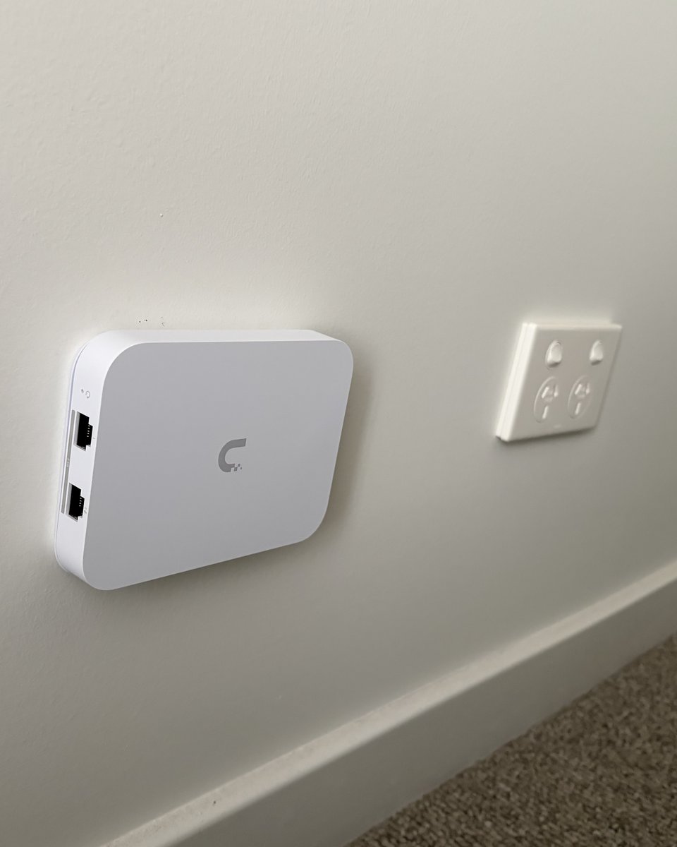 A slim white in-wall WiFi point on a painted wall, next to a standard double power point for size